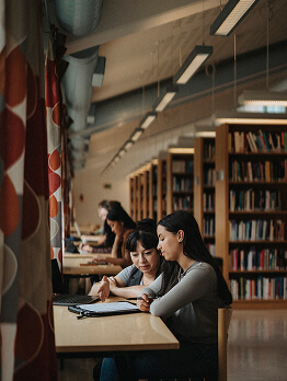 Estudiantes estudiando juntos en una mesa en una biblioteca.